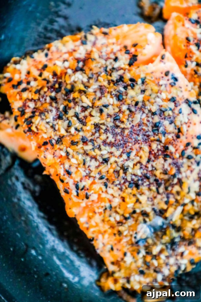 Several salmon fillets beautifully crusted with everything bagel seasoning in a pan, ready to be served.