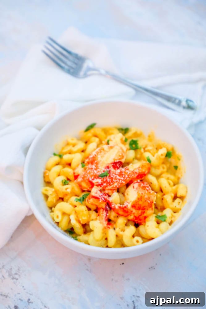 Rich and creamy lobster macaroni and cheese in a white bowl, garnished with fresh herbs.