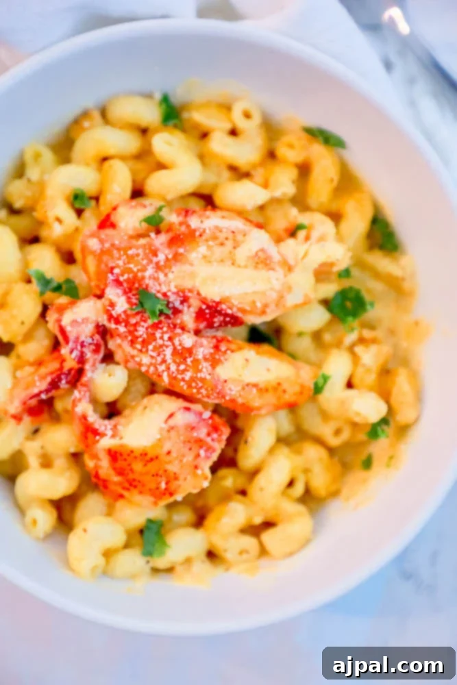 Delicious lobster macaroni and cheese served in a white bowl, topped with fresh herbs.