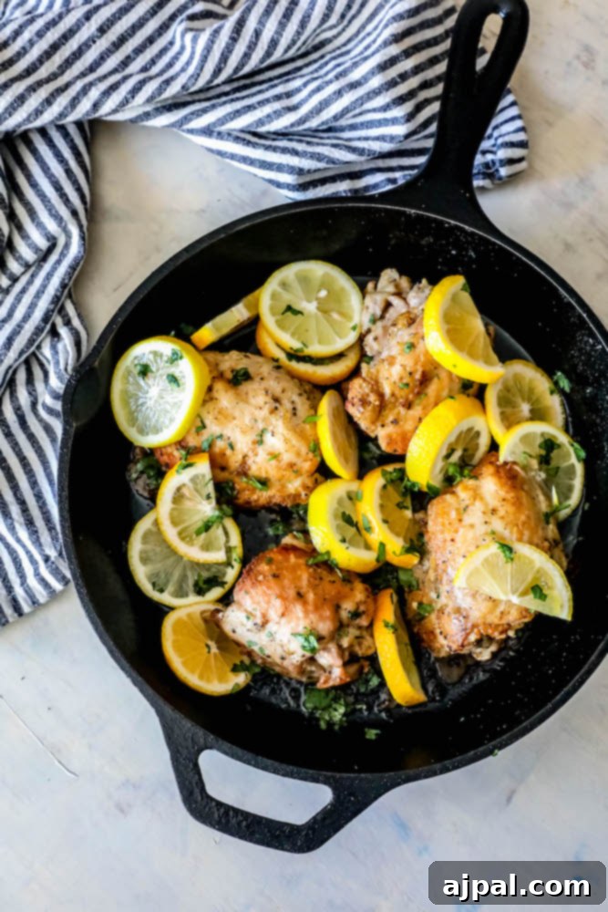 Zesty Lemon Chicken Perfection 4 chicken thighs in a cast iron skillet with sliced lemons