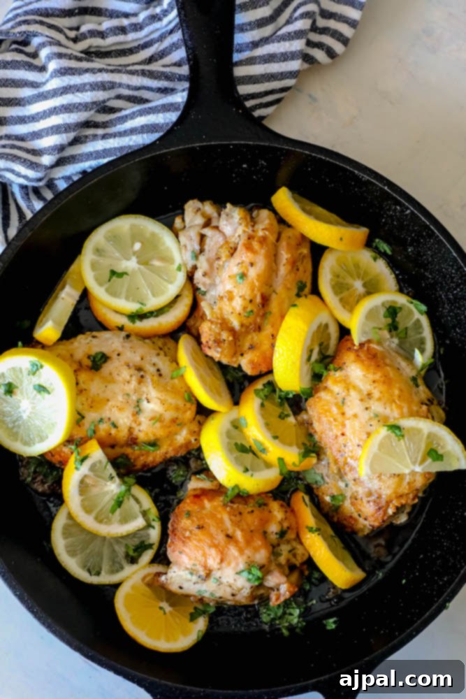 Zesty Lemon Chicken Perfection 7 cast iron skillet with chicken thighs and sliced lemons in it