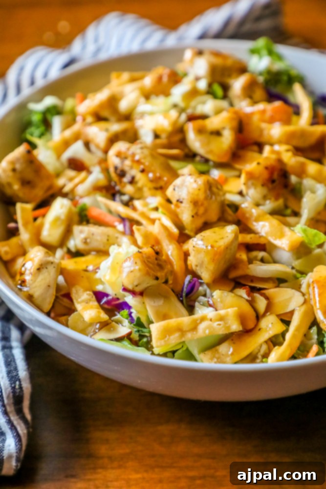 A large, delicious chicken Asian salad in a white bowl with a striped towel in the background, ready to be served.