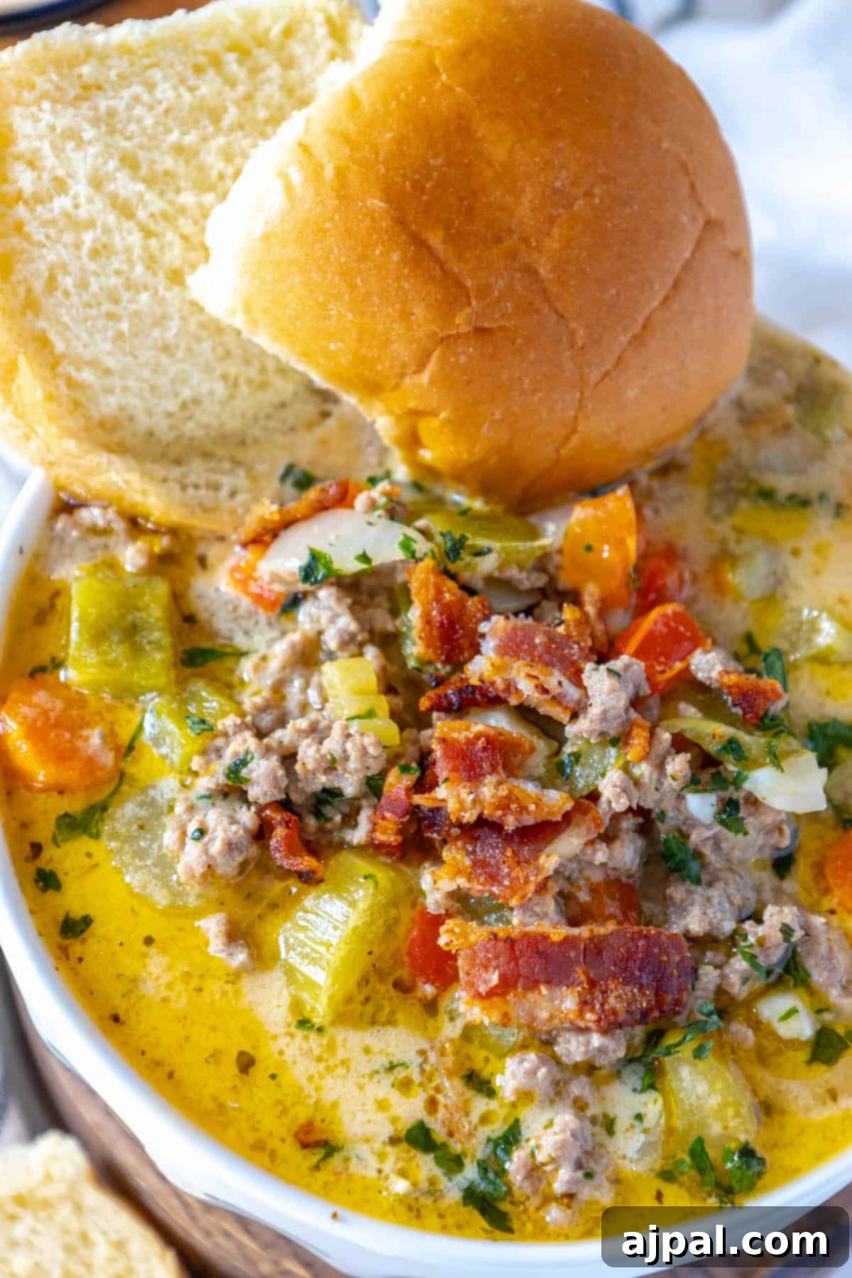 A cheesy bowl of Cheeseburger Soup with meat, vegetables, and bread.