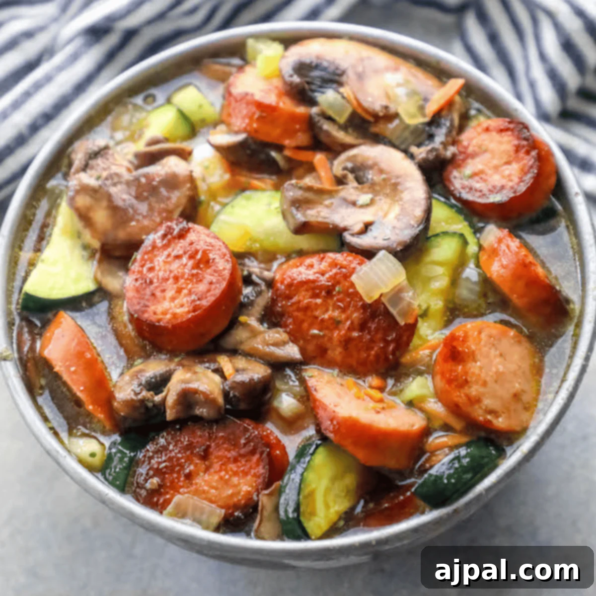 A steaming bowl of keto sausage and vegetable soup, perfectly portioned and ready to eat, highlighting the rich broth and colorful medley of ingredients.
