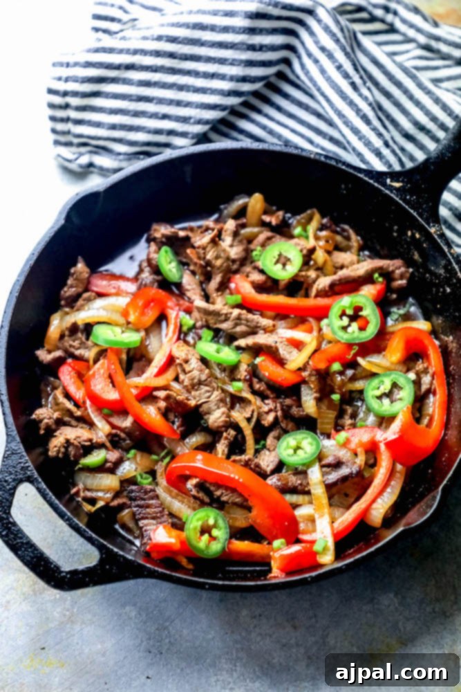 Ultimate One-Pan Steak Fajitas 2 Sizzling steak fajitas in a cast iron skillet with jalapeños, bell peppers, and onions