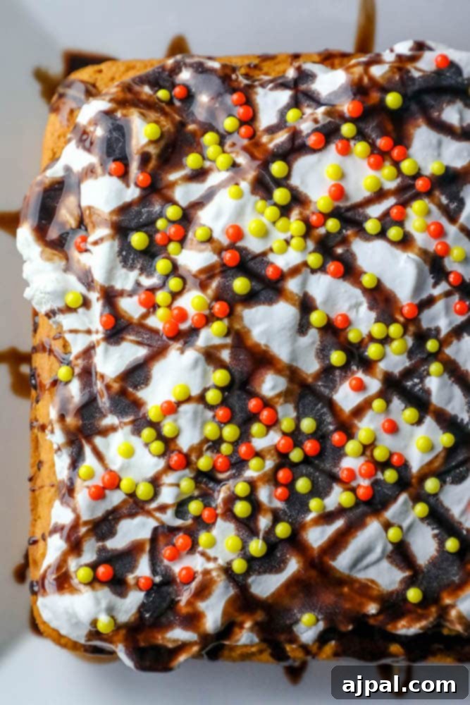 A beautifully decorated pumpkin cake with white frosting, a rich chocolate caramel drizzle, and vibrant orange and yellow sprinkles, ready to be enjoyed.