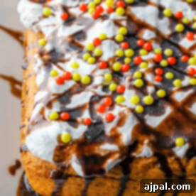 A cake made with box cake mix and pumpkin puree, topped with white frosting, multicolored sprinkles, and chocolate drizzle.