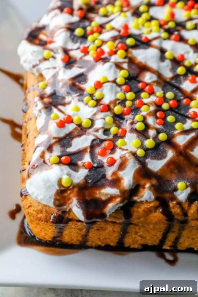 A slice of pumpkin dump cake, elegantly frosted with white cream and adorned with colorful sprinkles, sitting on a white plate ready for a bite.