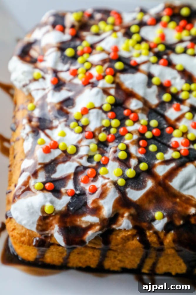 A delectable pumpkin cake slice topped with smooth cream cheese icing, a rich chocolate sauce drizzle, and playful sprinkles on a white plate, ready to be enjoyed.