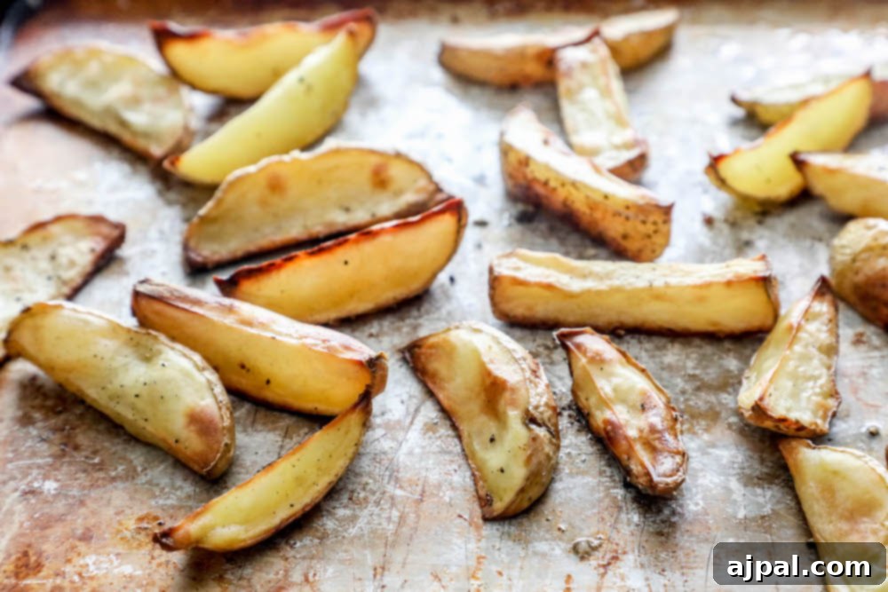 Golden Crispy Potato Wedges 3 Crispy potato wedges on a baking sheet, seasoned and ready to eat.