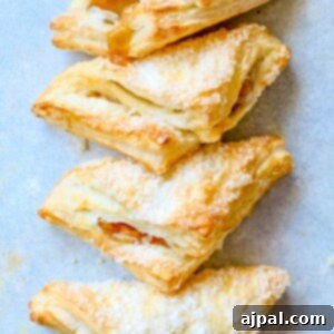 A stack of easy apple turnovers with powdered sugar on a blue background, perfect for a quick and delicious breakfast or dessert.