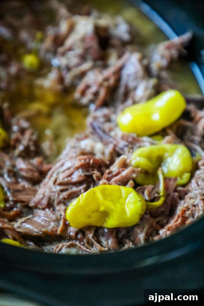 A close-up of a richly cooked Mississippi Pot Roast, showing the shredded beef and a hint of the tangy pepperoncinis, perfect for a family meal.