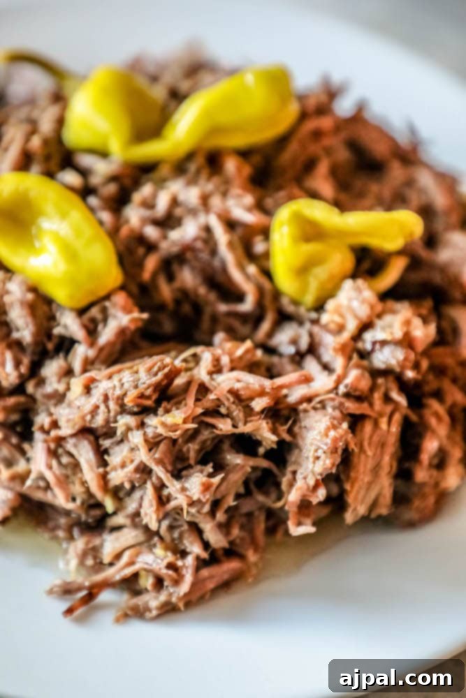 Southern Slow Cooker Pot Roast 6 A plate of perfectly pulled pork with a generous topping of vibrant peppers, embodying the delightful flavors of a Mississippi Roast.