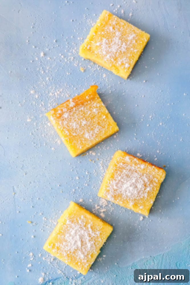 Picture of four perfectly sliced lemon bars arranged on a table, highlighting their soft texture and powdered sugar topping.