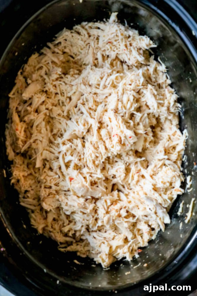 Generous amount of shredded chicken in a slow cooker, ready for serving.