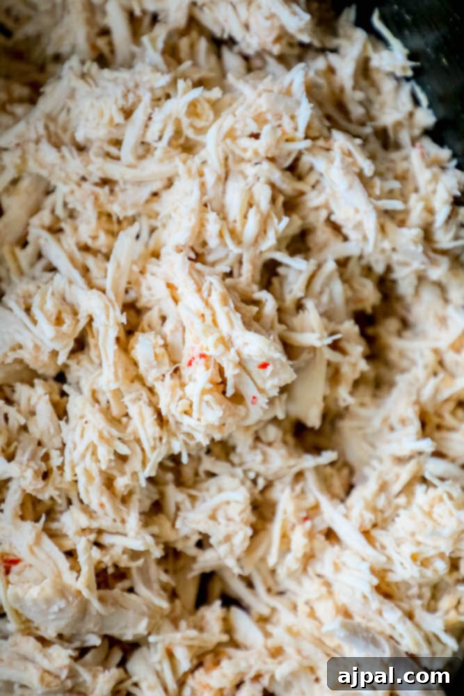 A close-up view of a pot of slow cooker shredded chicken, highlighting its tender texture.