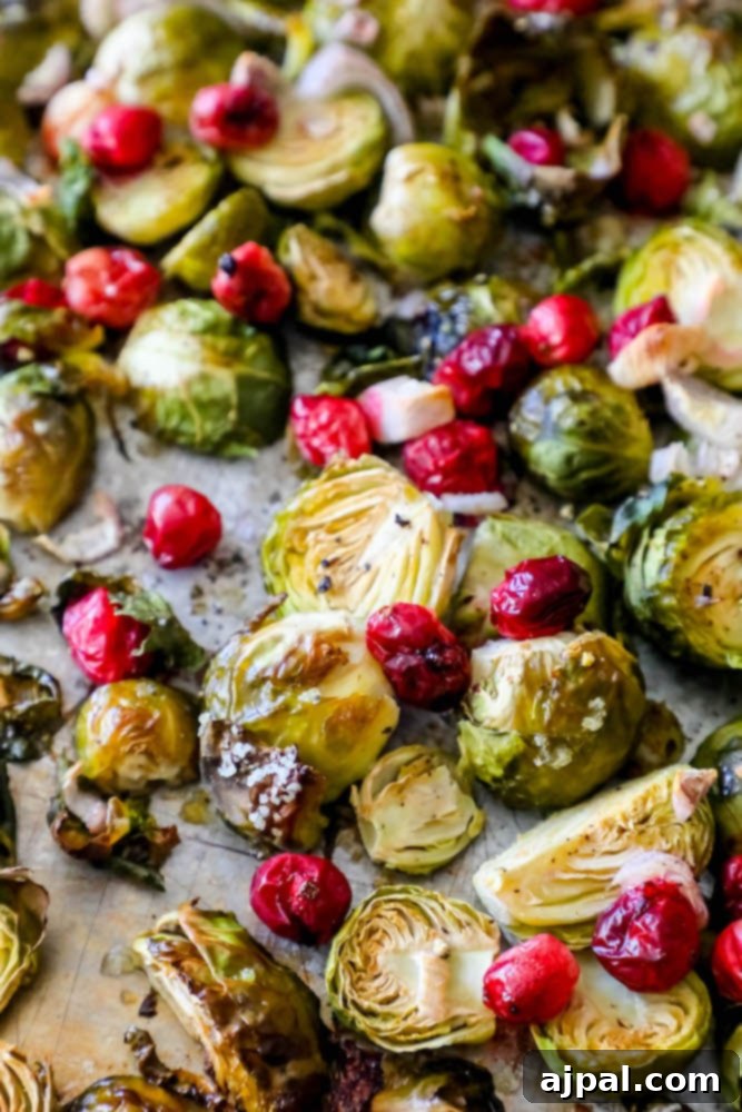 A vibrant mix of roasted Brussels sprouts and cranberries on a spacious baking sheet, showcasing their perfect browning.