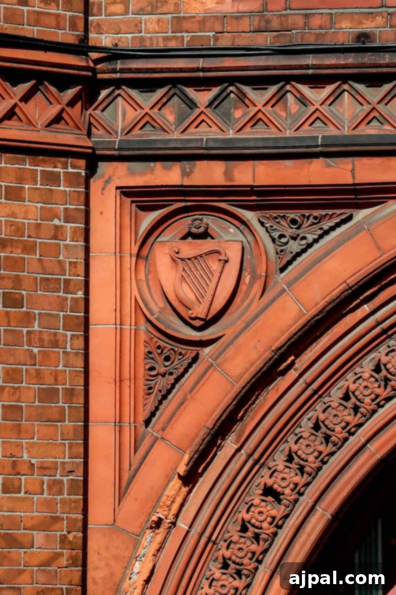 Detail of a red brick building with a clock tower featuring a harp emblem in Dublin, Ireland