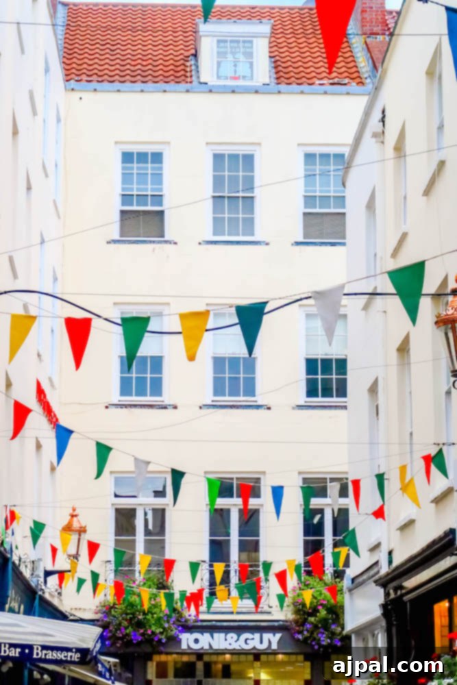 Book a British Isles Cruise: Your Adventure Awaits 13 A charming street in Guernsey, UK, adorned with festive bunting under a bright sky.