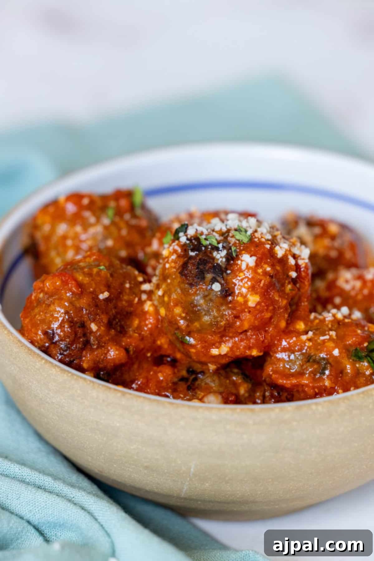 Deliciously Easy Meatballs 3 A bowl of the best easy meatballs, topped with rich tomato sauce and a generous sprinkle of grated cheese.