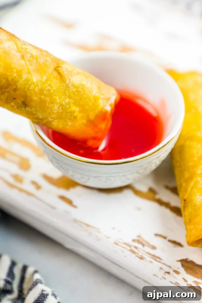 Crispy Homemade Egg Rolls 3 A beautifully arranged plate of crispy homemade egg rolls, served with a small bowl of dipping sauce, highlighting their golden-brown finish.