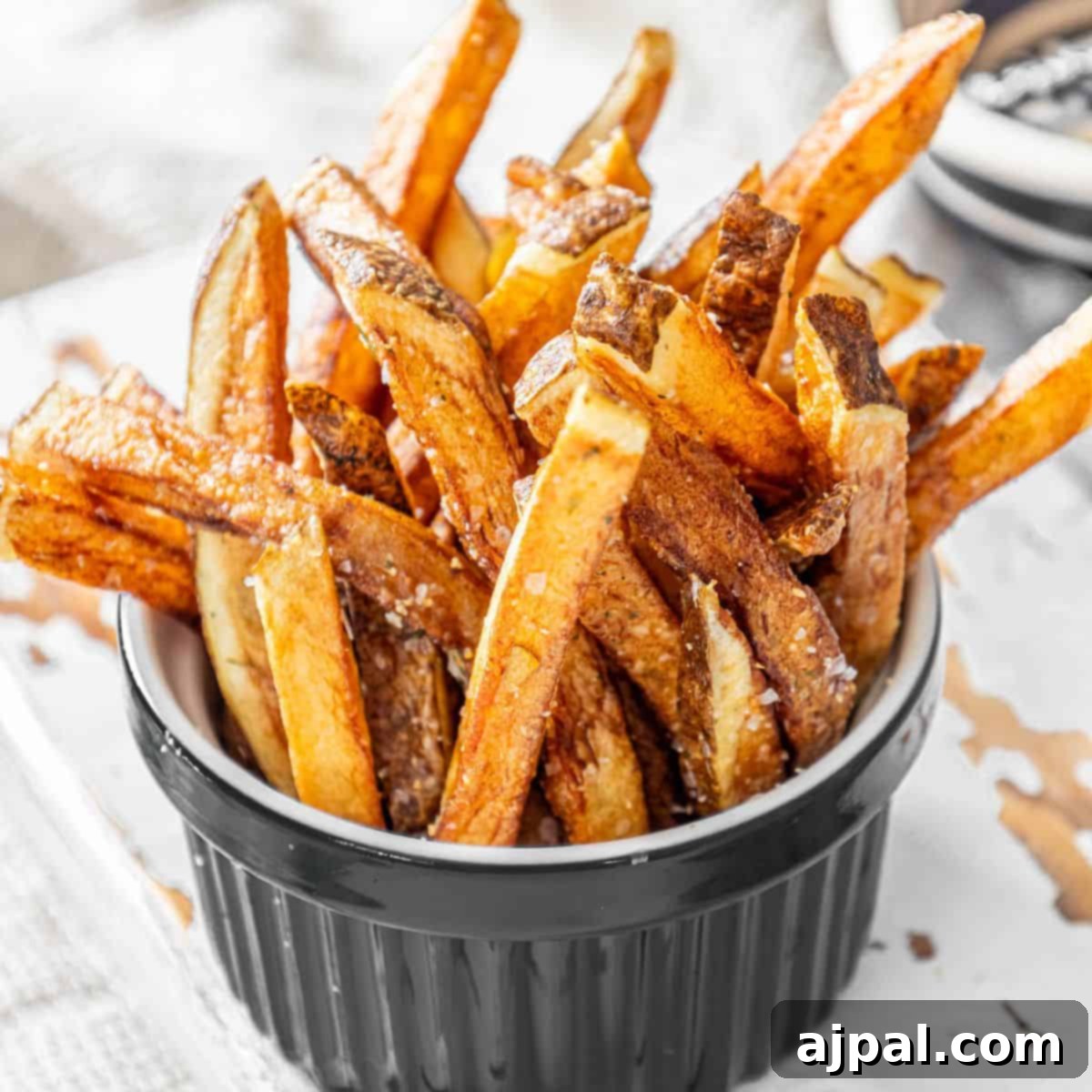 Crispy sweet potato fries in a black bowl.