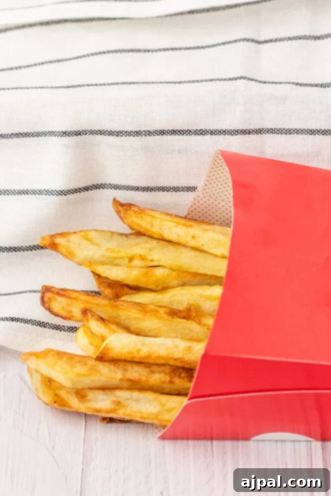 Crispy air fried French fries in a red box on a wooden table.
