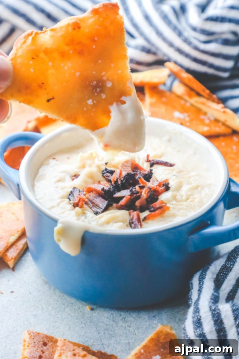 Quick Keto Tortilla Crisps 6 picture of hand dipping keto chip into dip, highlighting the chip's sturdy texture.