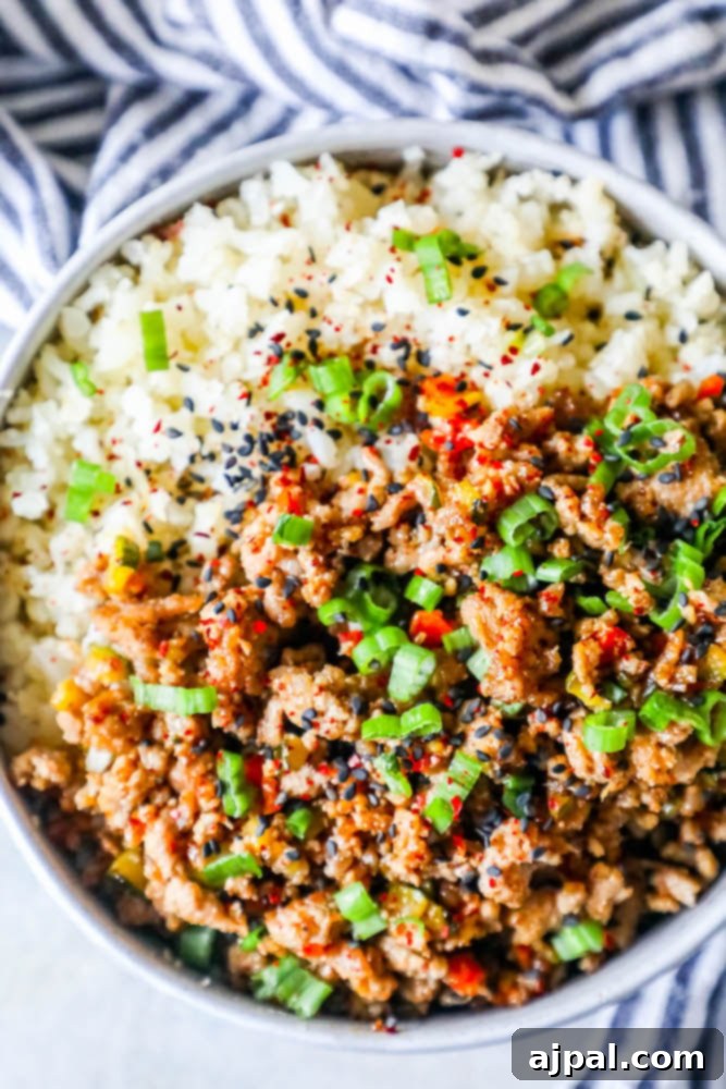 A vibrant and hearty Keto Teriyaki Turkey Rice Bowl, generously topped with fresh green onions and sesame seeds, showcasing a perfect balance of savory turkey and wholesome cauliflower rice.