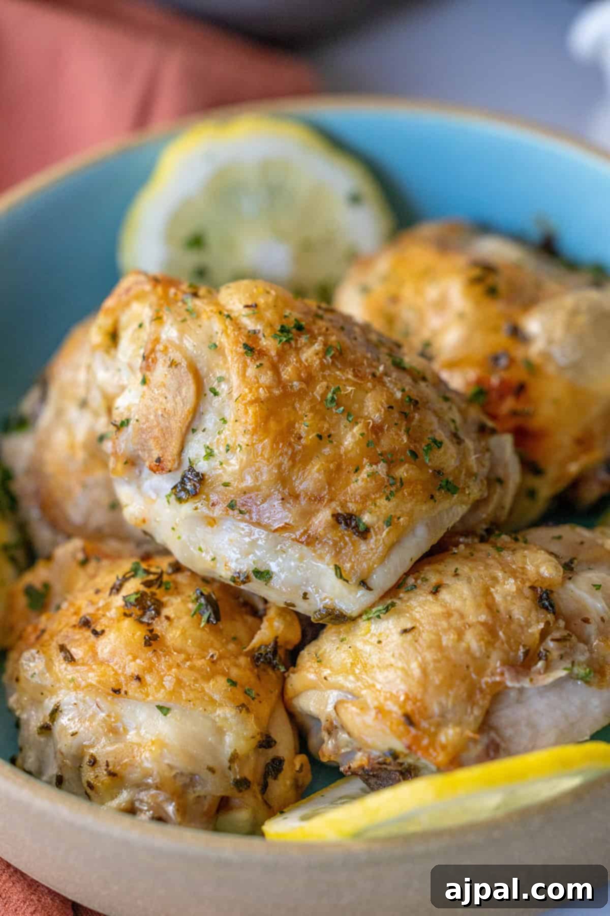 A bowl of golden brown roasted chicken pieces garnished with herbs, complemented by fresh lemon slices nearby—a delightful take on an easy air fryer lemon chicken recipe.