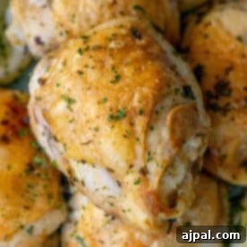 A close-up of golden-brown air fried lemon chicken thighs garnished with chopped herbs.