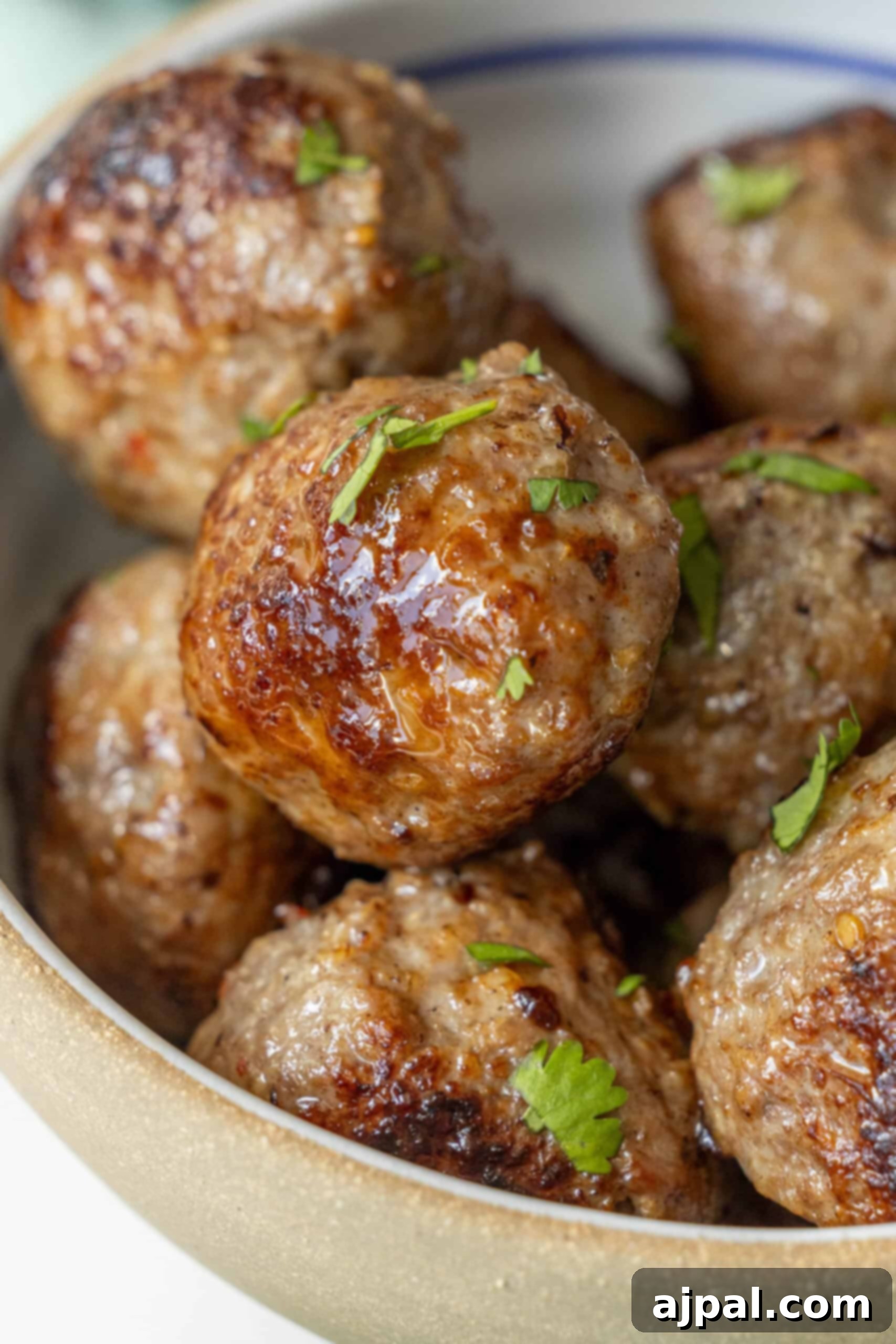 A close-up of air-fried meatballs garnished with chopped herbs in a bowl.