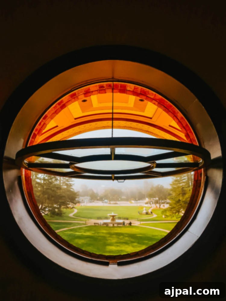 A circular window frames a serene view of a verdant field, offering a peaceful glimpse of the landscape from Atascadero City Hall.