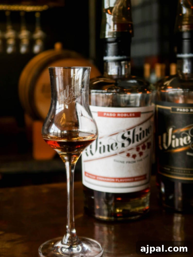 A sophisticated glass of cinnamon brandy rests on a sleek bar at Wine Shine Distillery in Paso Robles, California, inviting a taste of SLOCal's finest.