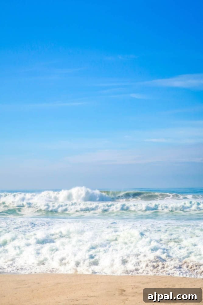 A man is standing on a sandy beach with waves crashing in front of him in Oxnard, California.
