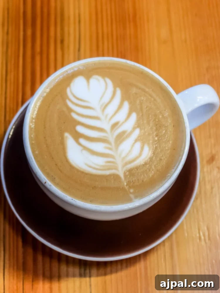 A latte with a leaf on top of a wooden table in Atascadero.