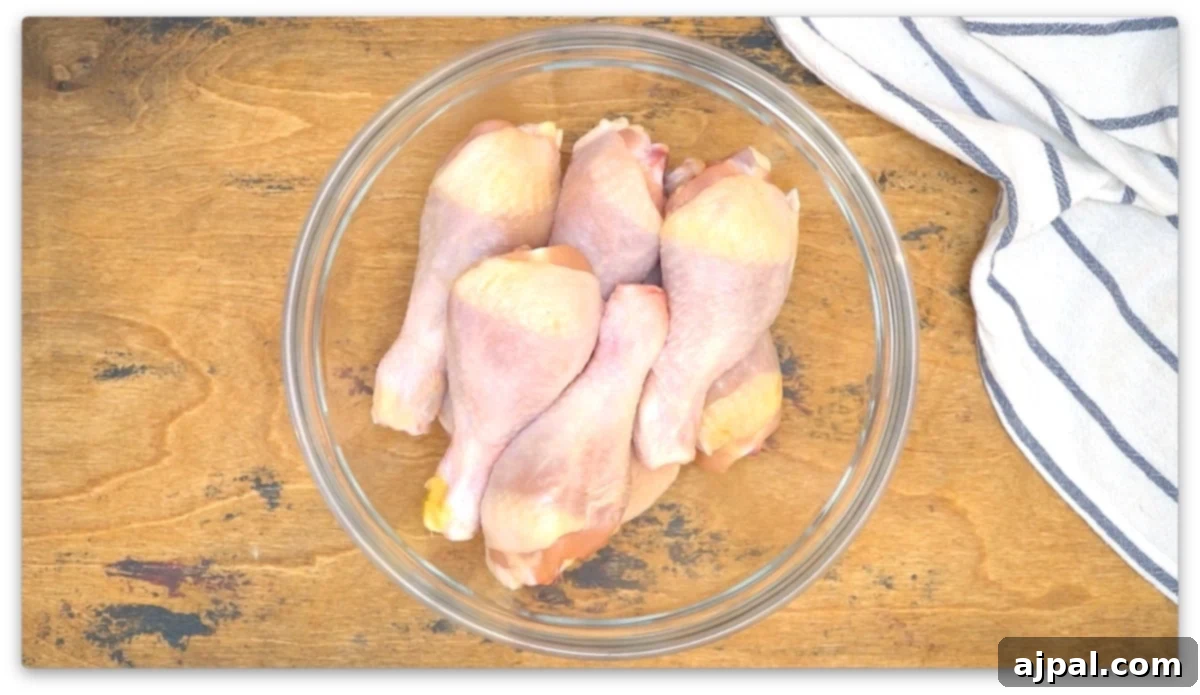 Chicken legs cooked in an air fryer, displayed in a glass bowl on a wooden table.