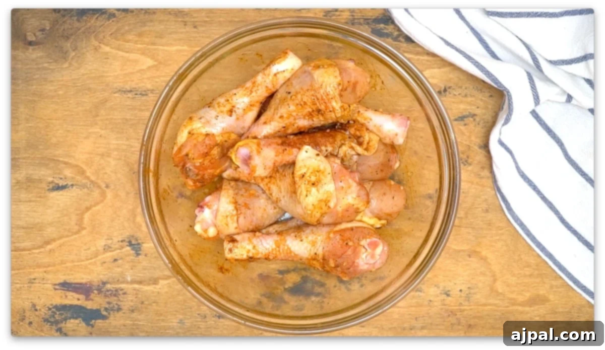 picture of seasoned raw chicken drumsticks in a glass bowl