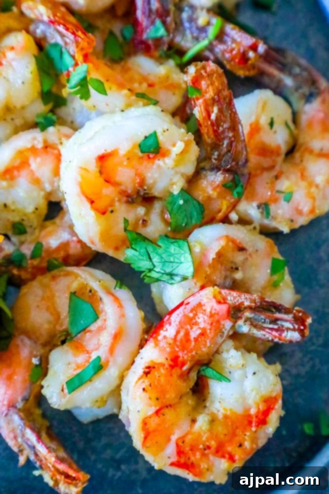 air fried shrimp on a plate covered in parmesan and garlic with chopped parsley