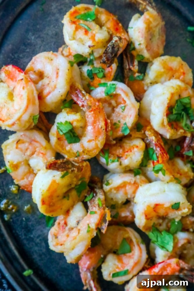 air fried shrimp on a plate covered in parmesan and garlic with chopped parsley