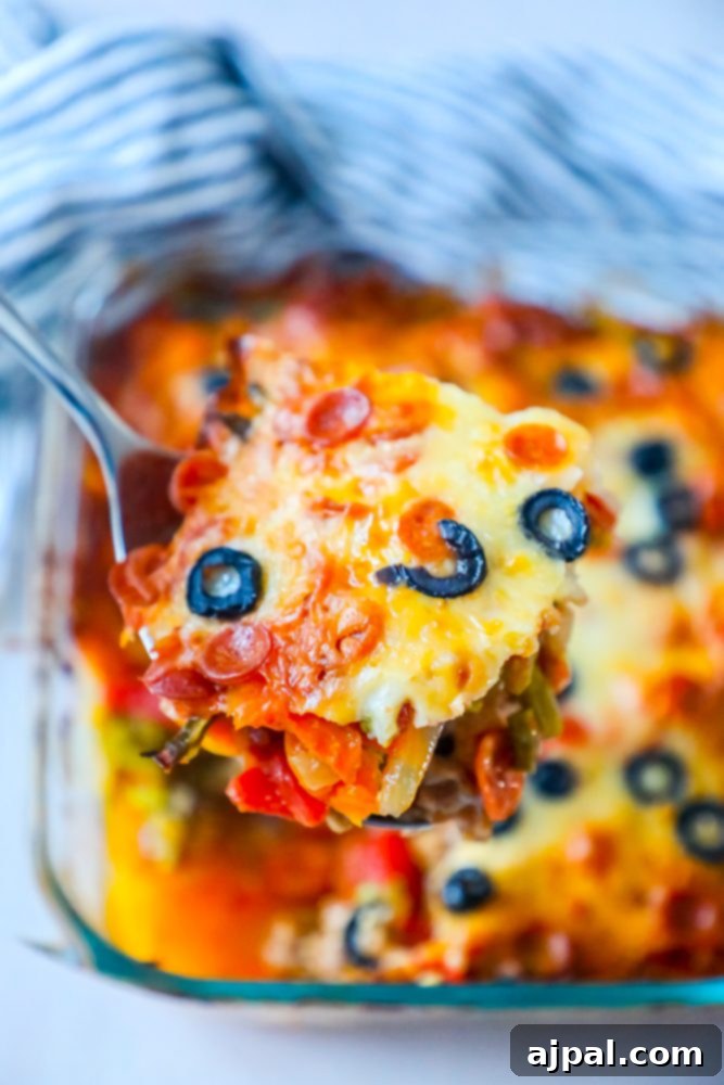 Ultimate Pizza Bake 2 A serving of cheesy keto pizza casserole with melted cheese, pepperoni, black olives, and visible vegetables.