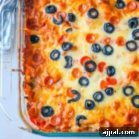 A baked Cheesy Low Carb Pizza Casserole topped with melted cheese, pepperoni slices, and black olives in a clear glass dish.