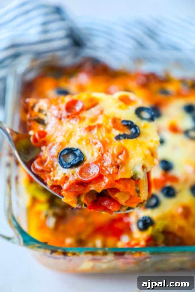 Ultimate Pizza Bake 5 A large scoop of cheesy keto pizza casserole in a serving dish, showcasing the melted cheese and toppings.