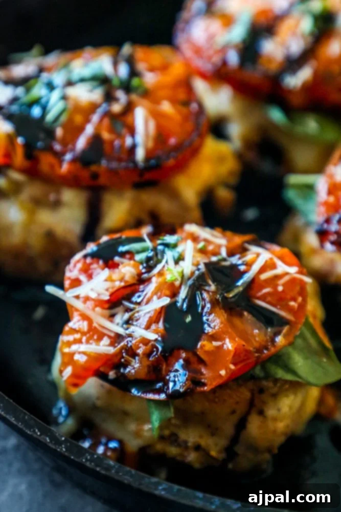 Caprese chicken in a pan, topped with melted cheese, basil, and balsamic glaze.