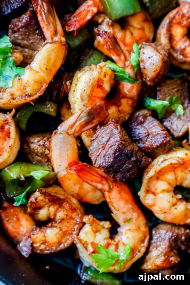 Close-up of Cajun butter steak and shrimp skillet, garnished with fresh parsley.