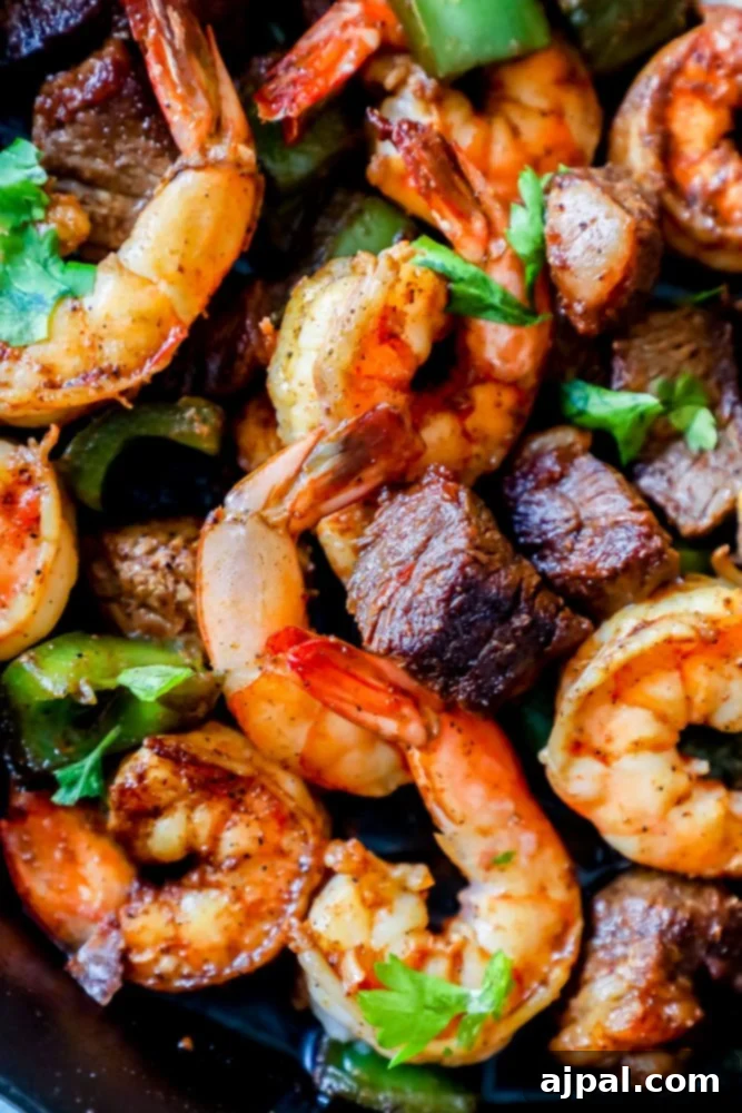 Decadent Cajun Butter Steak and Shrimp 2 Shrimp, steak, and vibrant spices with fresh parsley on top in a skillet, ready to serve.