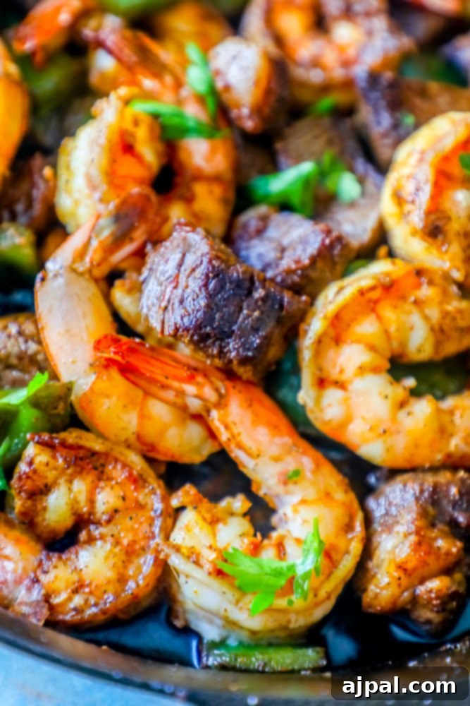 Vibrant Cajun butter steak bites with shrimp and bell peppers sizzling in a cast-iron skillet.