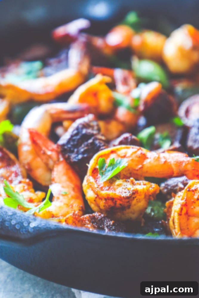 A large skillet filled with perfectly cooked Cajun butter steak and shrimp with bell peppers.