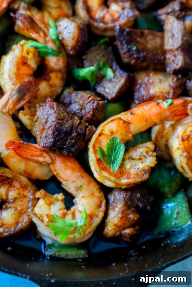 A generous serving of Cajun butter steak and shrimp on a plate, garnished with fresh herbs.