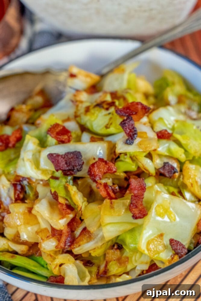Crispy bacon and tender, browned cabbage with onions in a white serving bowl.